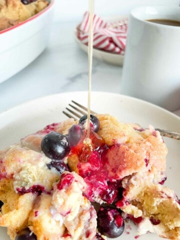 Drizzling syrup on top of blueberry french toast casserole.