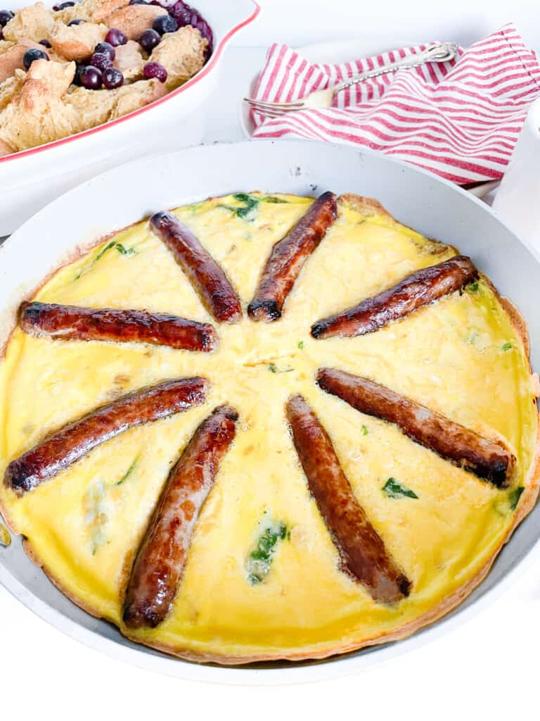 Sausage frittata in a frying pan with a breakfast casserole behind it.