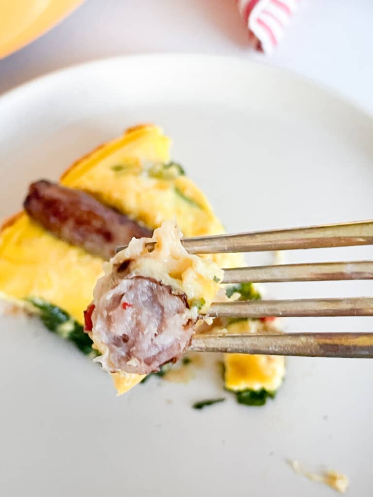 A bite of a sausage frittata in front of slice of the frittata.