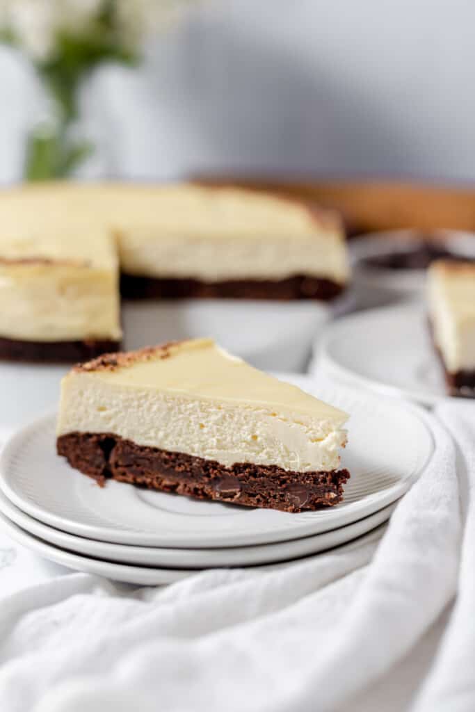 Brownie Bottom Cheesecake on a plate with the full cake behind it. 