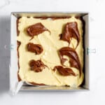 Dotting brownie batter over the cheesecake layer.