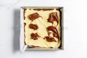 Dotting brownie batter over the cheesecake layer.