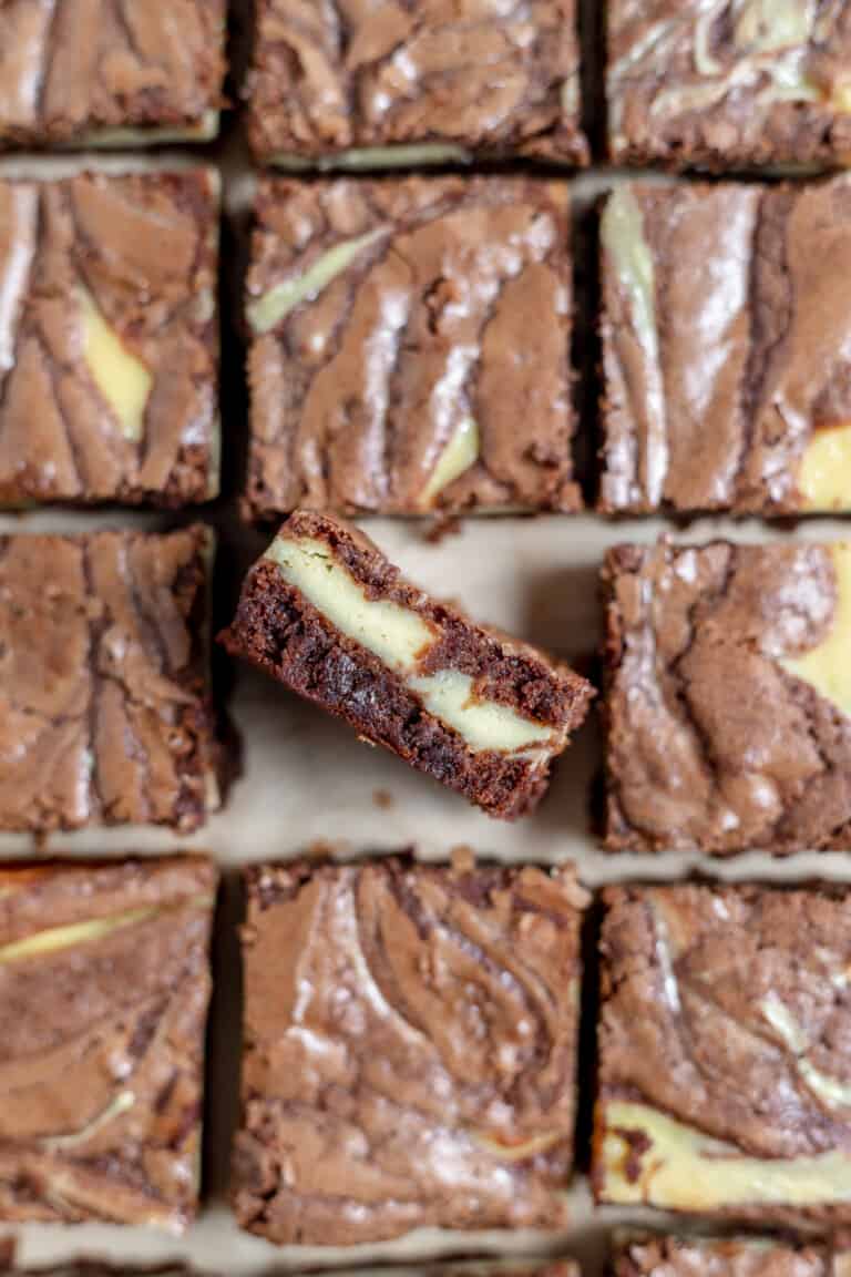 Close-up photo of fudgy swirled cheesecake brownies on a cooling tray.