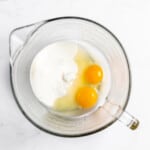 Eggs and sugar in a mixing bowl.