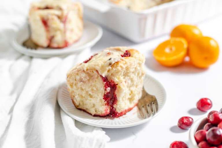 Servings of orange cranberry rolls with fresh lemons and cranberries around.
