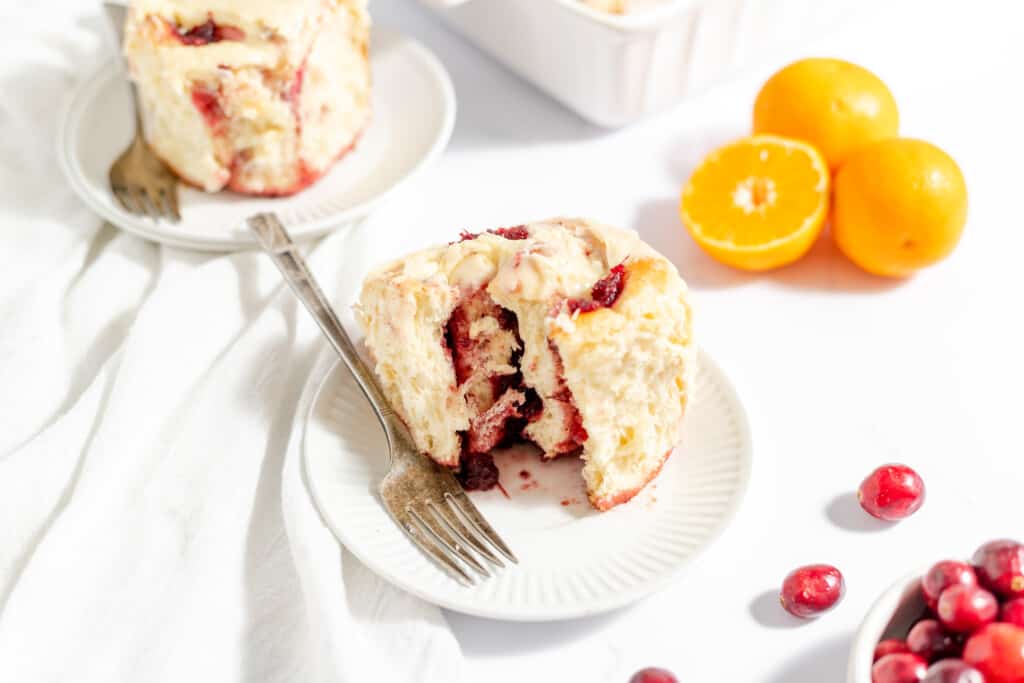 Cranberry Orange roll with cranberry orange filling on a plate with a fork.