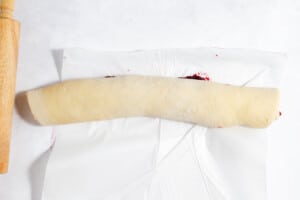 Rolled sweet rolls dough filled with cranberries ready to be cut.