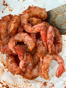 Shrimp in a bowl coated with blackening seasoning ready to cook.