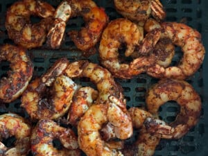 Finished air fryer blackened shrimp in the basket of an air fryer.