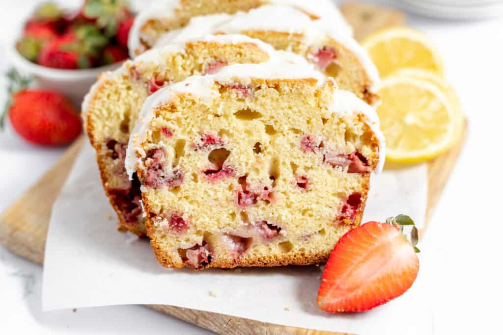 Iced strawberry bread served with fresh strawberries and sliced lemons.