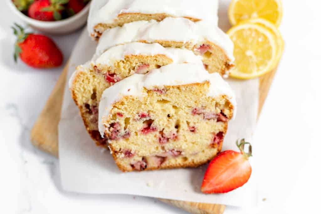 Iced strawberry bread served with fresh strawberries and sliced lemons.