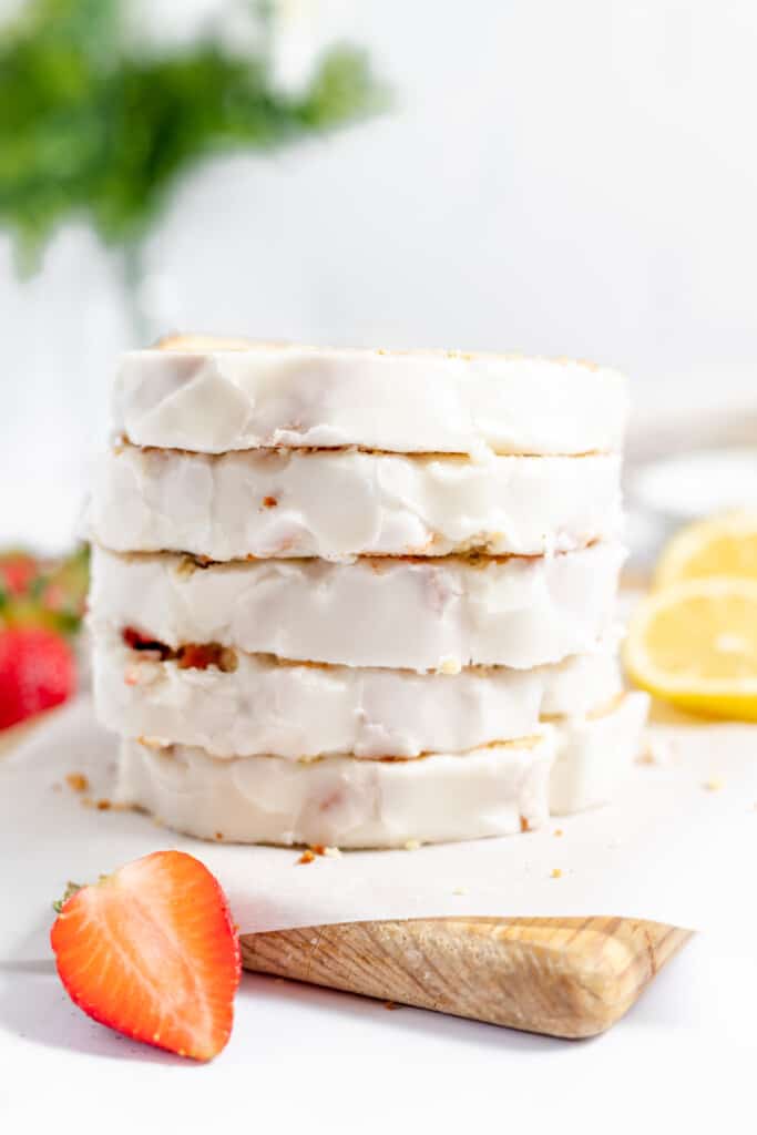 A stack of strawberry bread with the icing showing and fresh fruit.