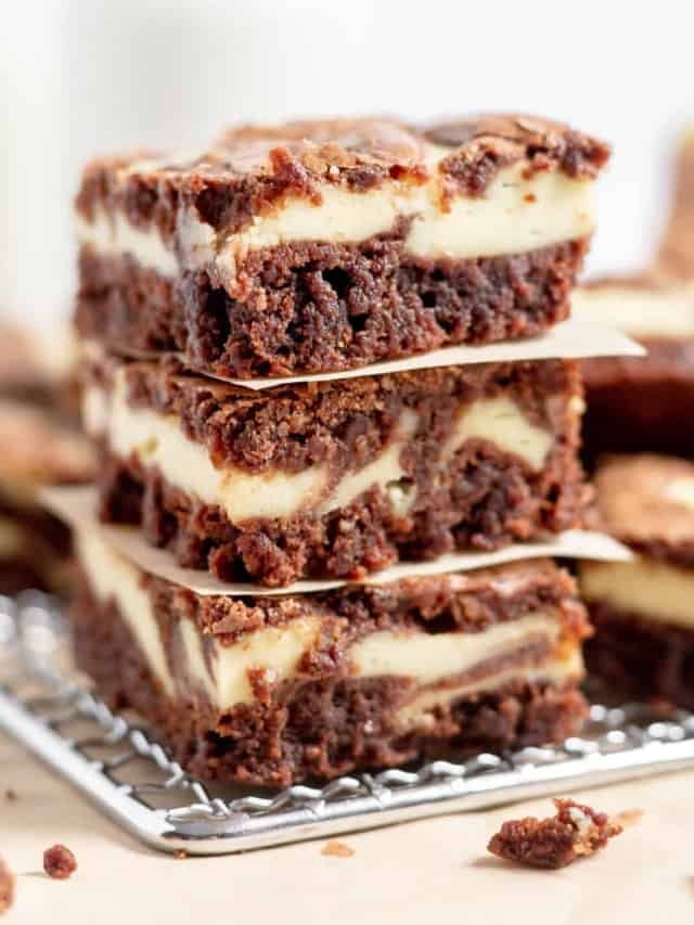 Stack of chocolate brownies with swirls of creamy cheesecake batter.