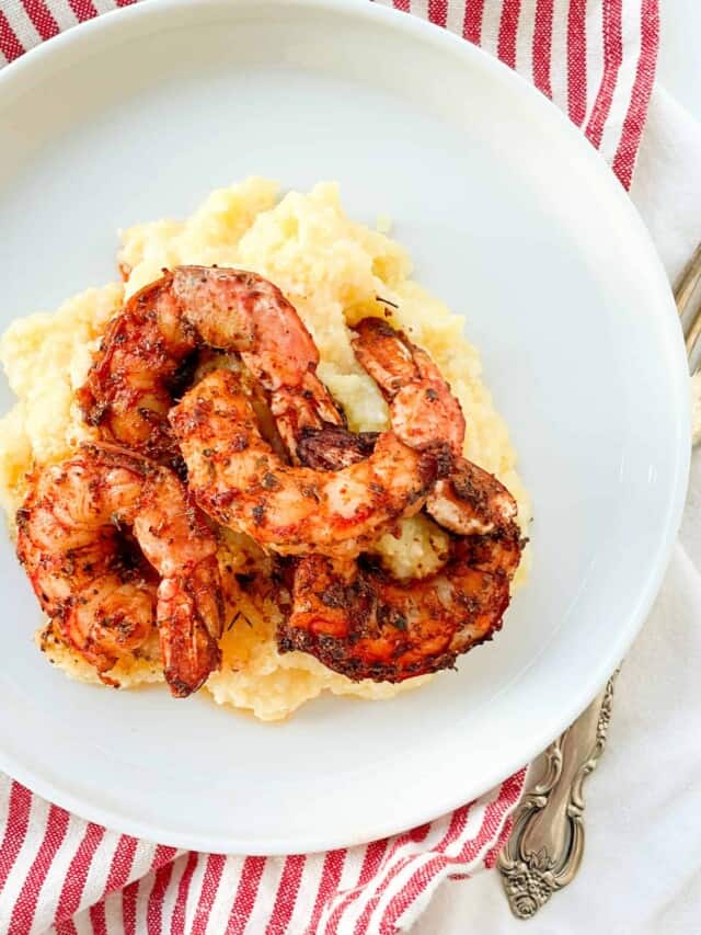 Grilled shrimp and grits on a white plate.