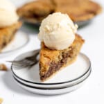 Chocolate chip pie on a stack of plates with a scoop of ice cream.