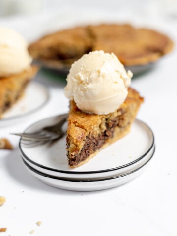 Chocolate chip pie on a stack of plates with a scoop of ice cream.