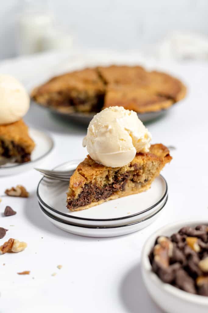 A slice of chocolate chip pie with ice cream on top of it. 