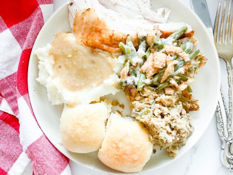 A plate with turkey, green beans, and mashed potatoes smothered in gravy.