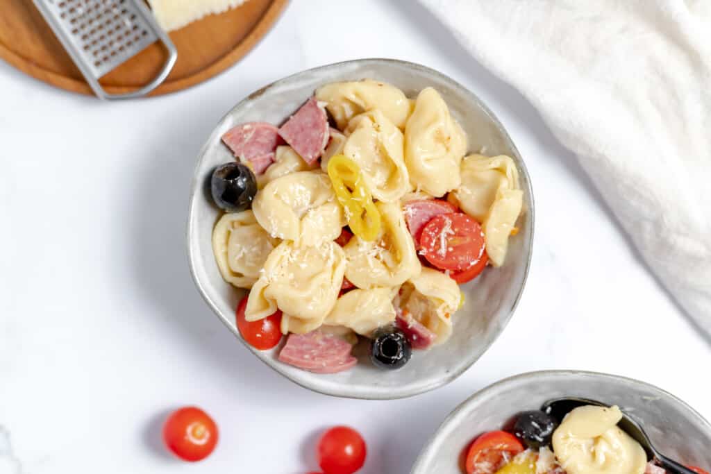 A bowl of pasta salad with a spoon in it.