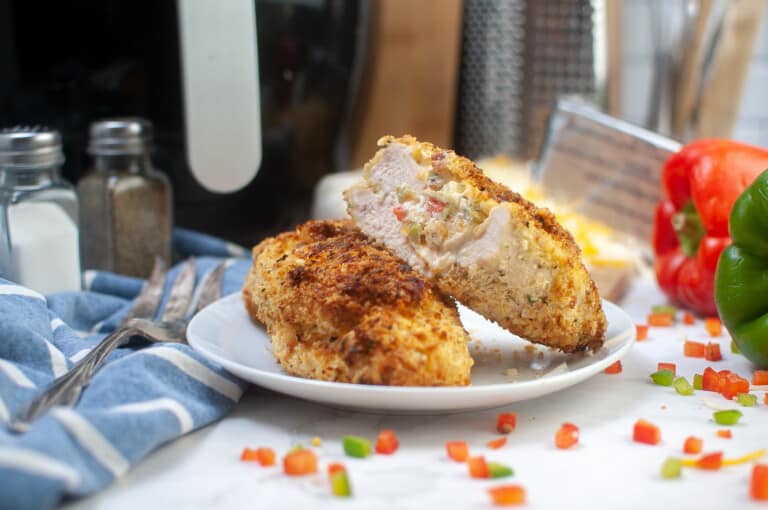 Plate of air fryer stuffed chicken breasts with vegetables and cheese.