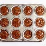 Chocolate zucchini muffin batter divided into a muffin tin.