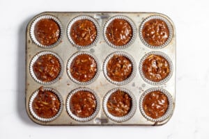 Chocolate zucchini muffin batter divided into a muffin tin.