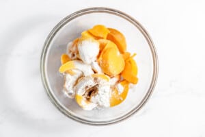 Peaches, corn starch, and spices in a bowl.