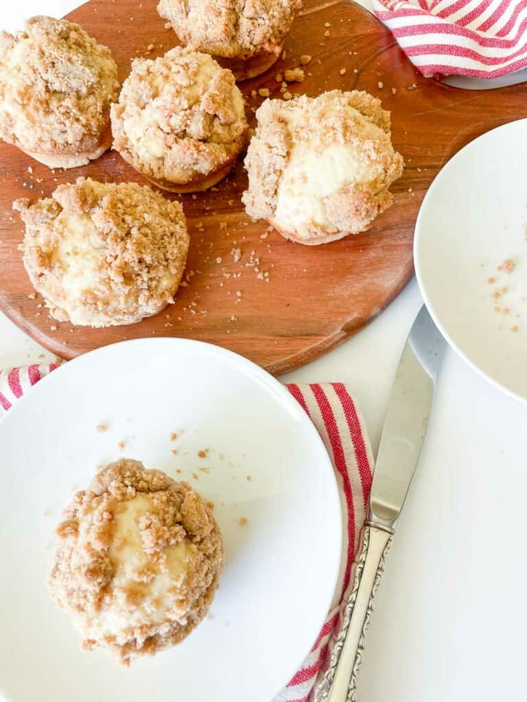 Rhubarb muffins with streusel on a wooden board and one on a plate.
