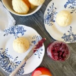 Lemon muffins on plates with a bowl of muffins, and jelly.