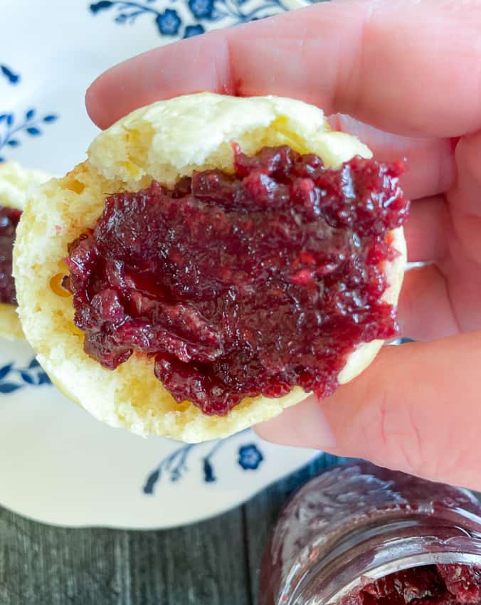 Half a lemon muffin slathered with raspberry jam on top of it.