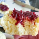A lemon muffin with jam with a bite taken out of it.