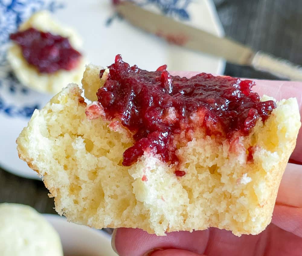A lemon muffin with jam with a bite taken out of it. 