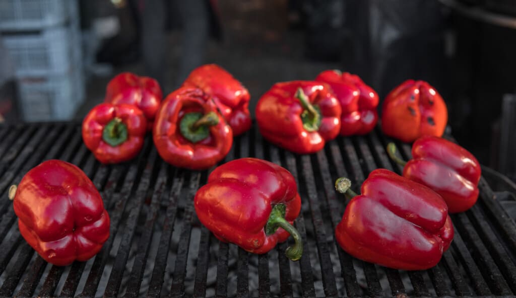 Red peppers roasting on a grill.