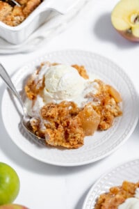 A plate of apple crisp with ice cream and apples.