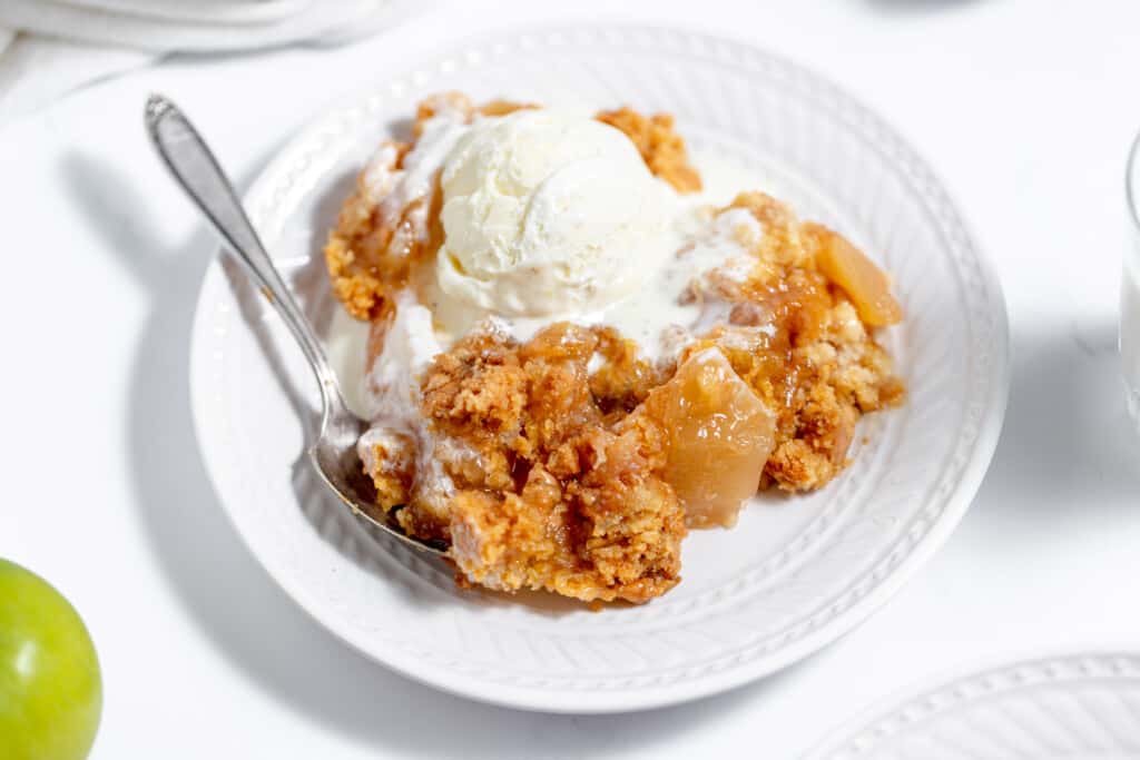 Apple crisp on a plate with ice cream and apples.