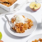 A plate of apple crisp with ice cream and apples.