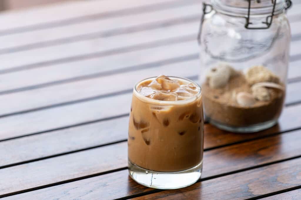A glass of iced coffee sitting on a wooden table.