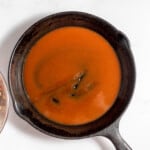 A skillet with a bowl of tomato sauce next to a bowl of meat.