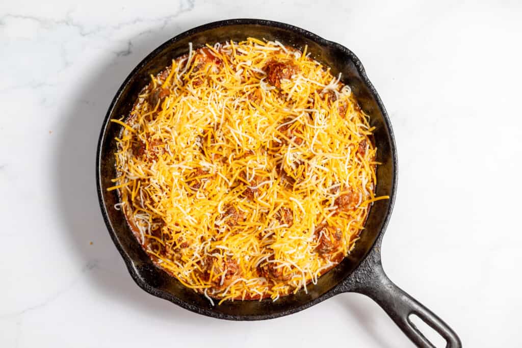 A skillet filled with enchilada meatballs and cheese.