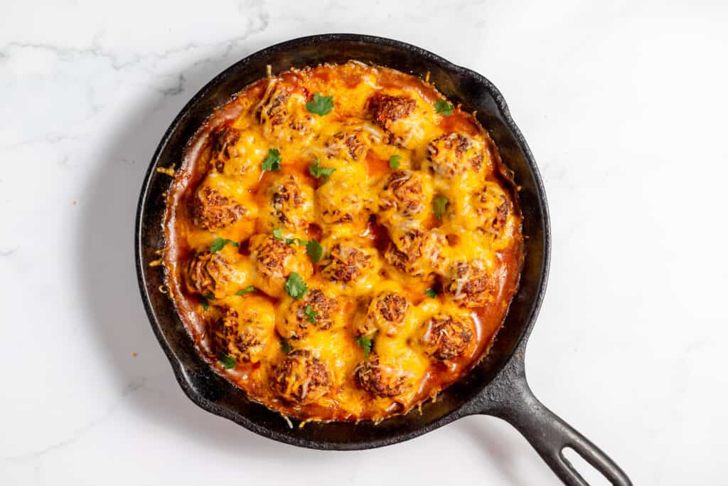 Enchilada meatballs cooked in a cast iron skillet.