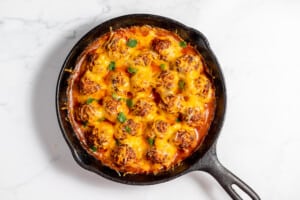 Cheesy meatballs cooked in a cast iron skillet.