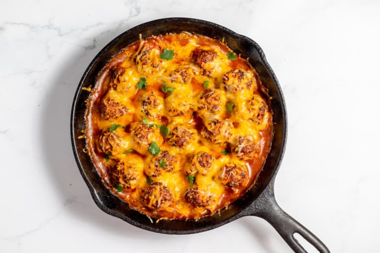 Cheesy meatballs cooked in a cast iron skillet.