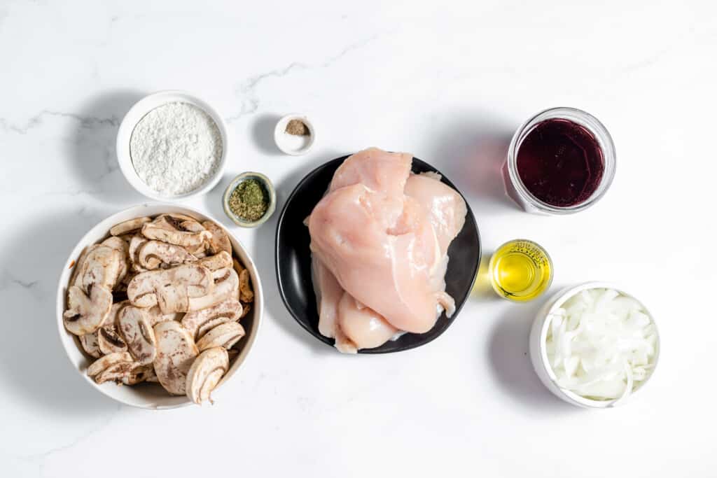 The ingredients for a chicken marsala dish are shown on a white background.