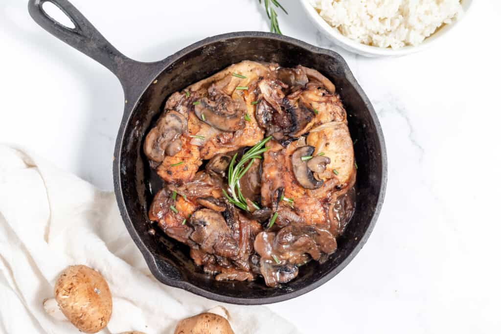 Chicken marsala with mushrooms and rice in a skillet.