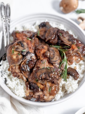 Chicken breasts with mushrooms and rice in a white bowl, served in a chicken marsala sauce.