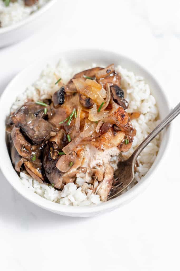 A white bowl filled with chicken marsala and mushrooms.