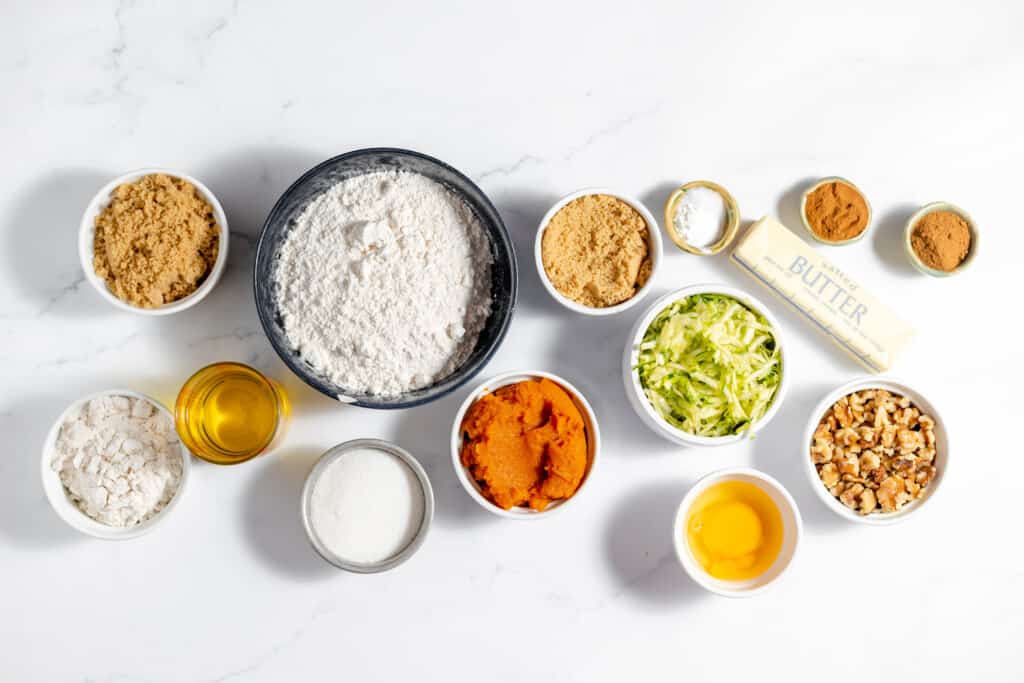 Various ingredients are shown in bowls on a white background, including pumpkin and zucchini.