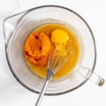 A mixing bowl with eggs and pumpkin in preparation for baking pumpkin bread.