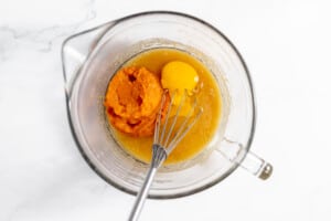 A mixing bowl with eggs and pumpkin in preparation for baking pumpkin bread.