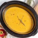 A crock pot full of soup and apples.